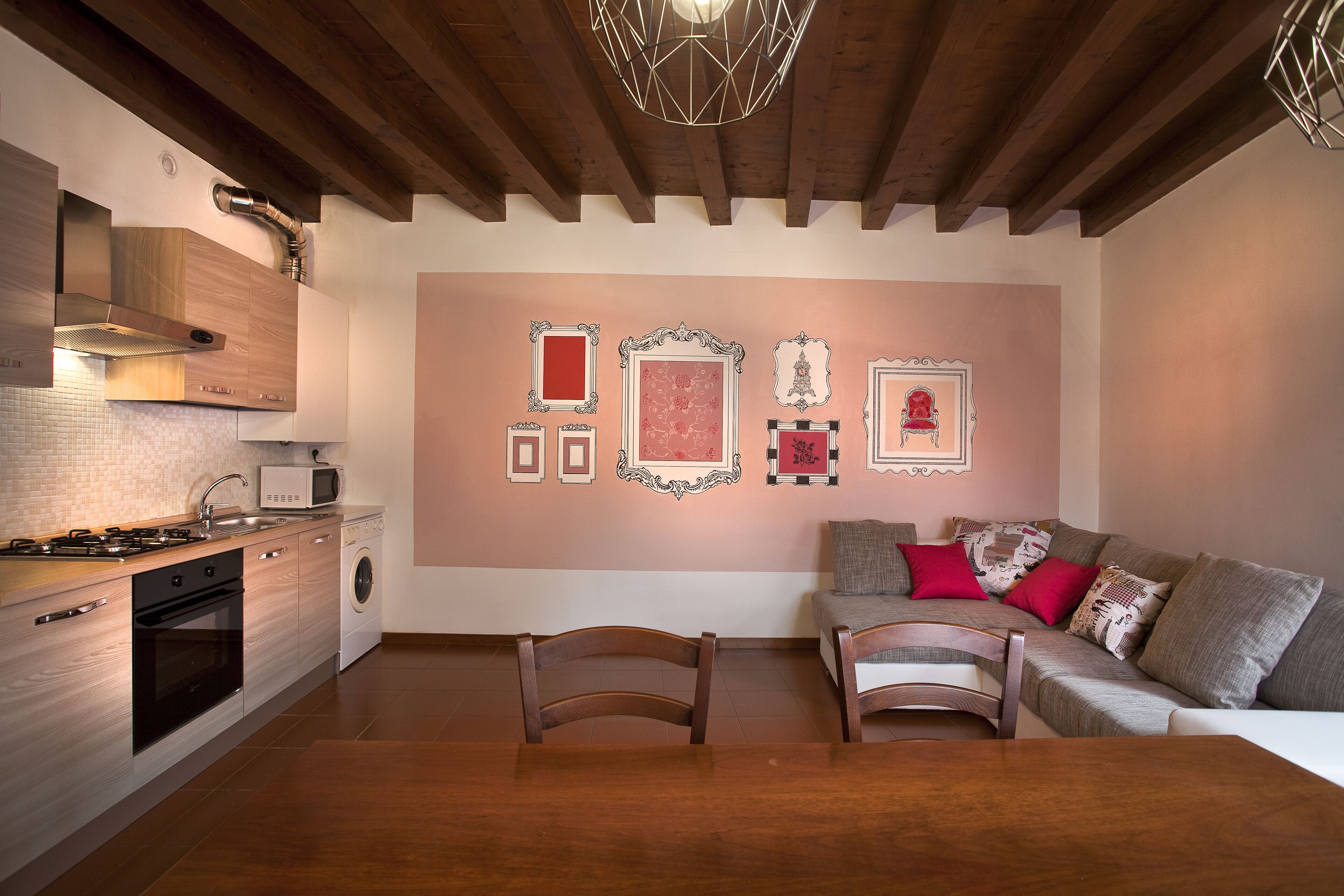 A modern kitchen with wooden cabinets, a built-in microwave, and a dining area with a table and chairs.
