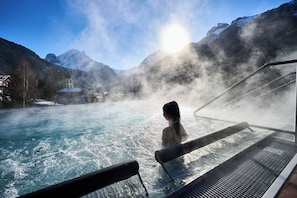 A person in a hot spring surrounded by mountains and a clear sky. - Hotel Cesa Tyrol (Canazei)