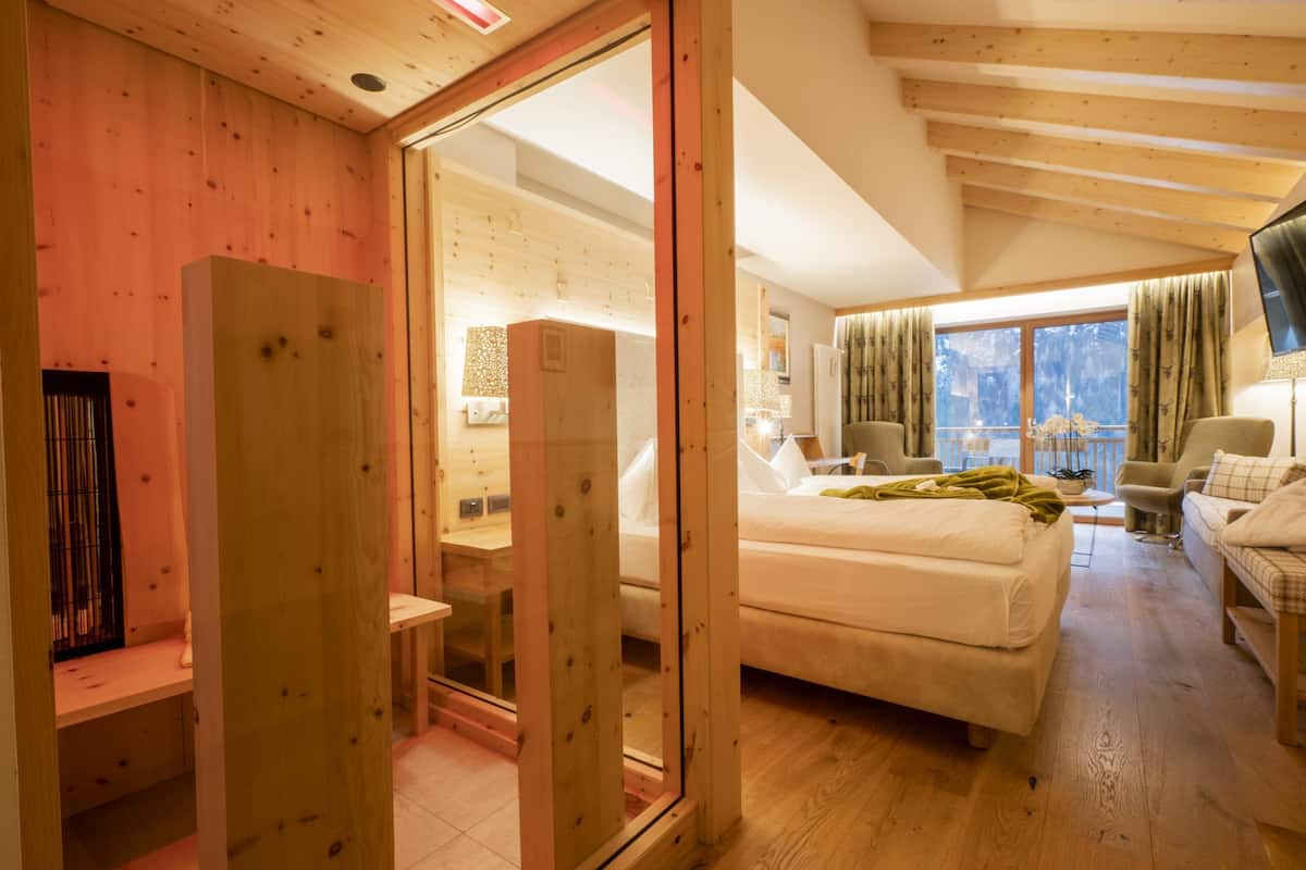 Un dormitorio moderno con techo de madera, una cama grande, un escritorio y una ventana con cortinas.