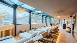 Een spa met massagestoelen, een receptie en uitzicht op besneeuwde bergen door grote ramen.