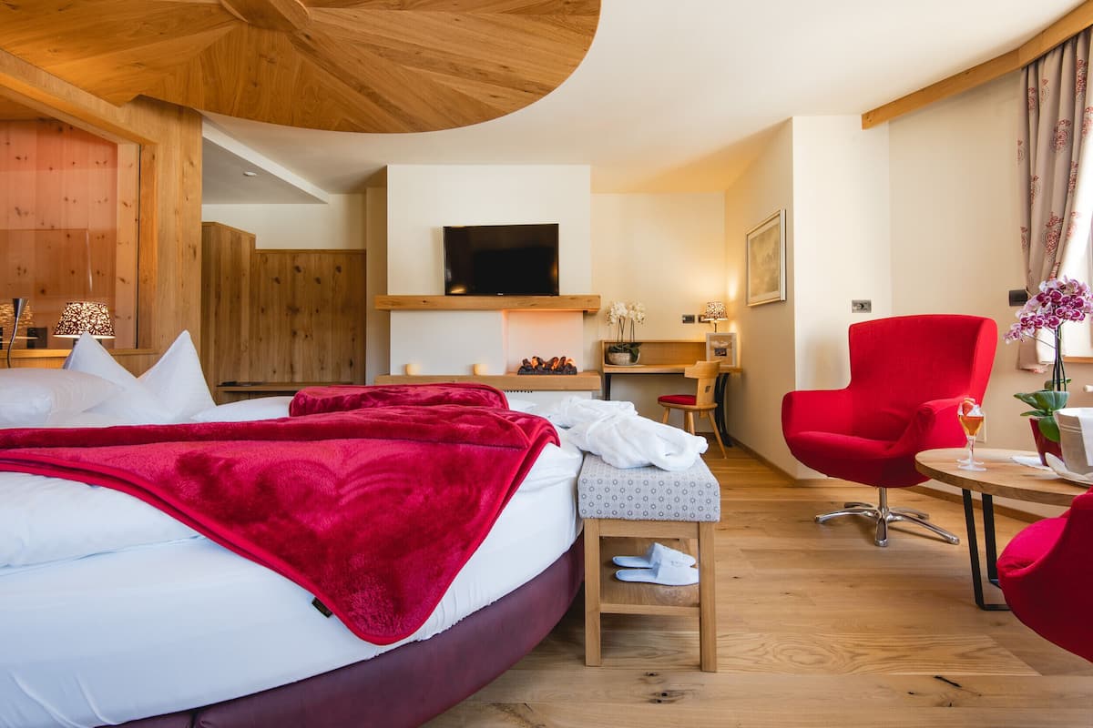 Una habitación de hotel con cama, televisión, escritorio y una silla roja.