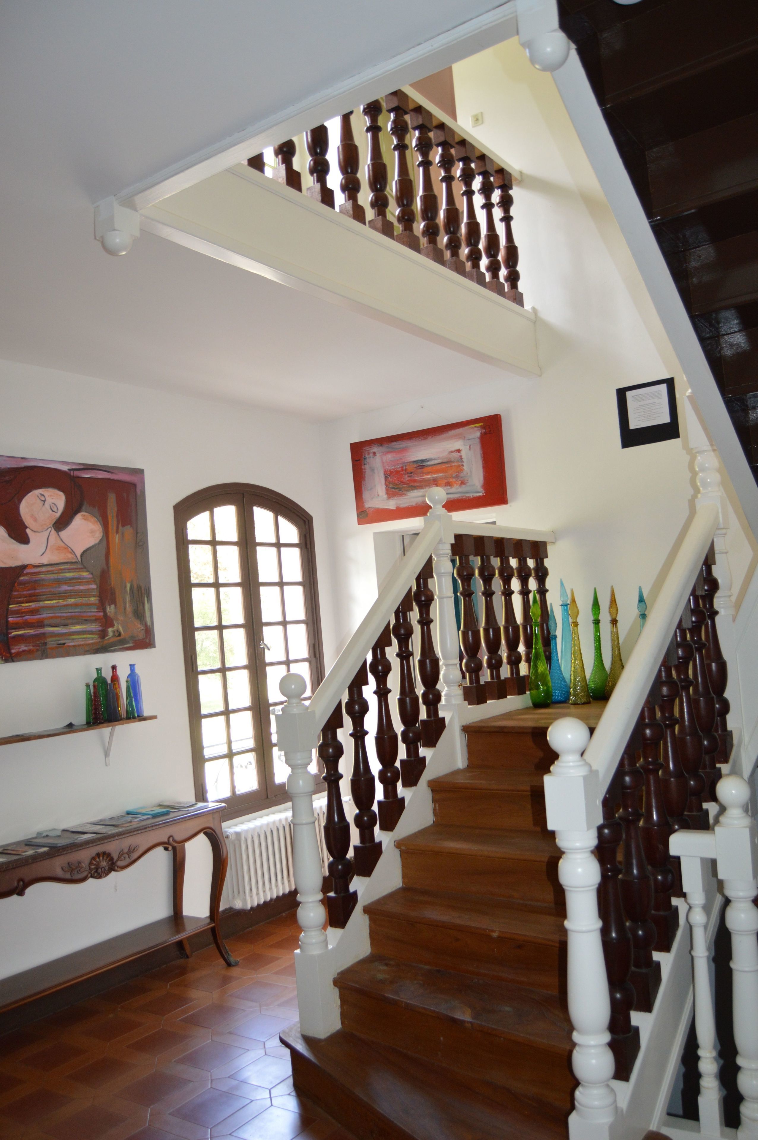 A wooden staircase with white balusters and a wooden handrail, leading to an upper floor.