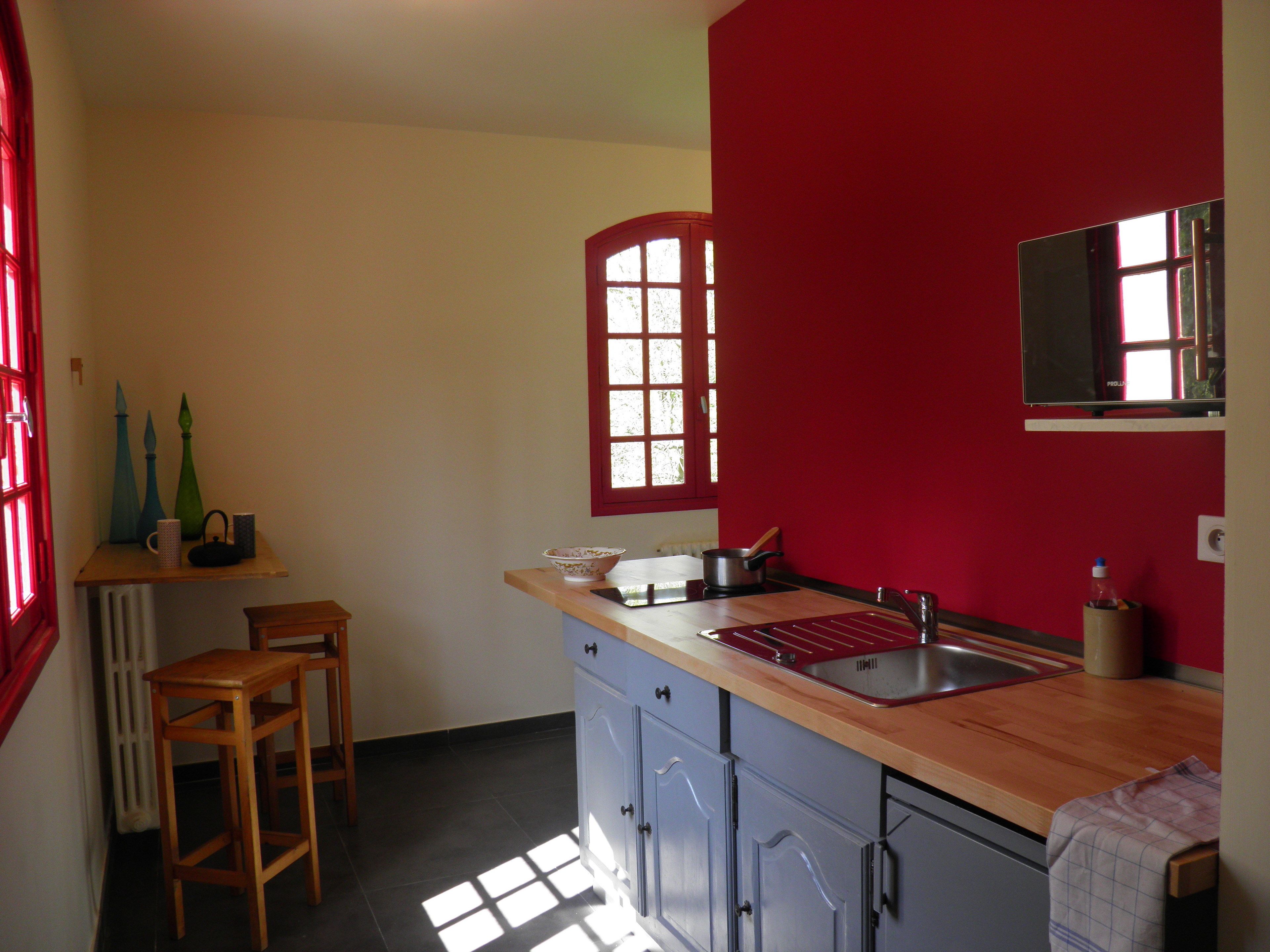 Une cuisine avec un mur rouge, une fenêtre et un évier.
