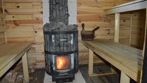 Una estufa de leña con fuego, rodeada de paredes y bancos de madera.