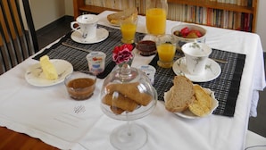 Una mesa de desayuno con diversos alimentos y una estantería llena de libros al fondo.