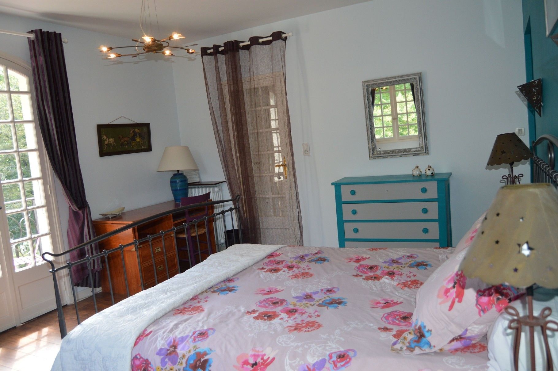 A bedroom with a bed, a dresser, a window, and a lamp.