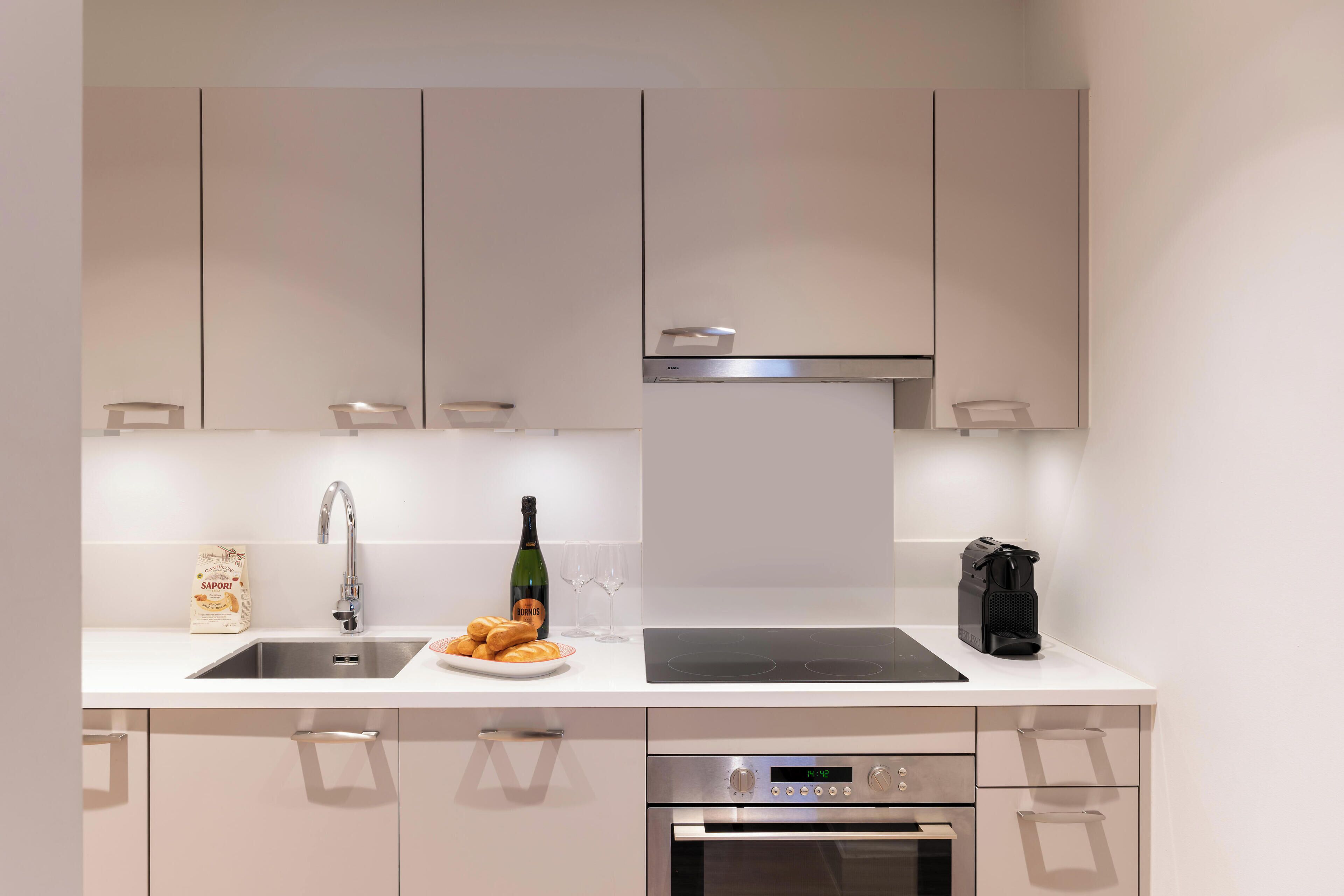 Una cucina moderna con un lavello in acciaio inossidabile, una bottiglia di vino e una macchina per il caffè.