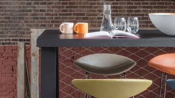 A bar area with stools, a table with a book, a bowl, and two cups.