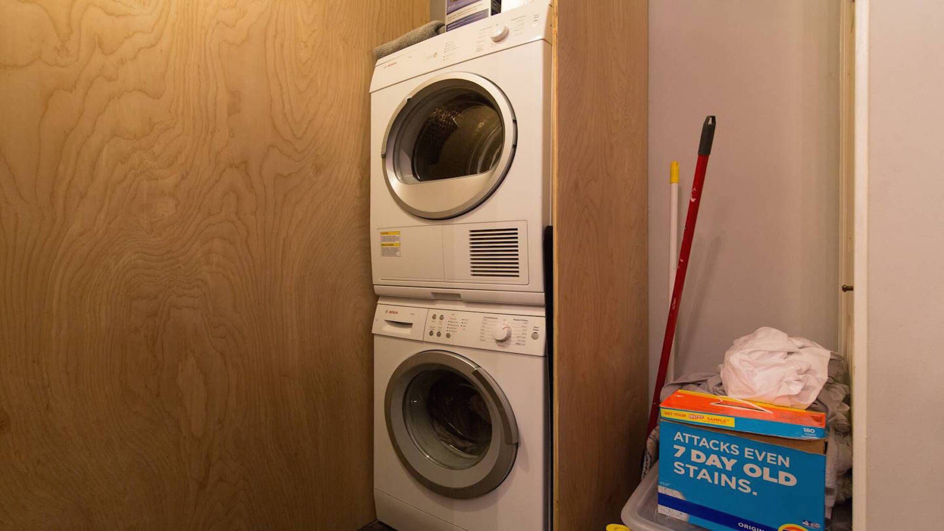 A laundry area with stacked washing machines and a box of stain remover.