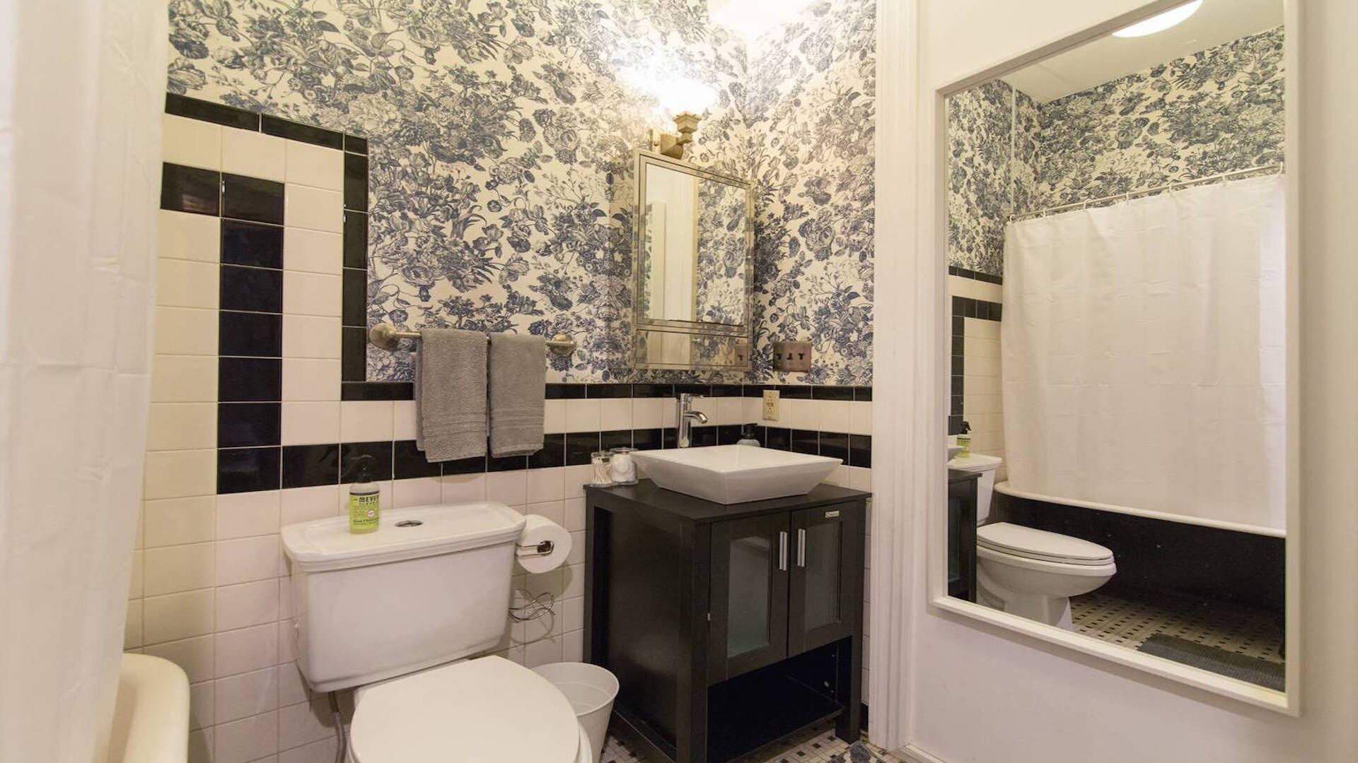 A bathroom with a toilet, sink, and mirror.