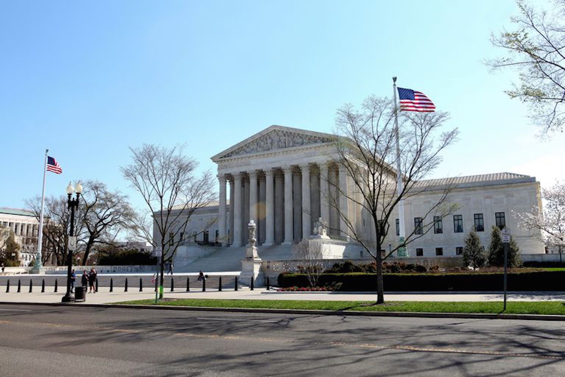A large, classical building with columns and a prominent entrance, surrounded by a well-maintained lawn and flagpoles.