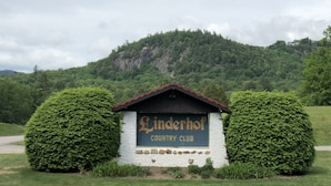 Señal del Linderhof Country Club con montañas al fondo.
