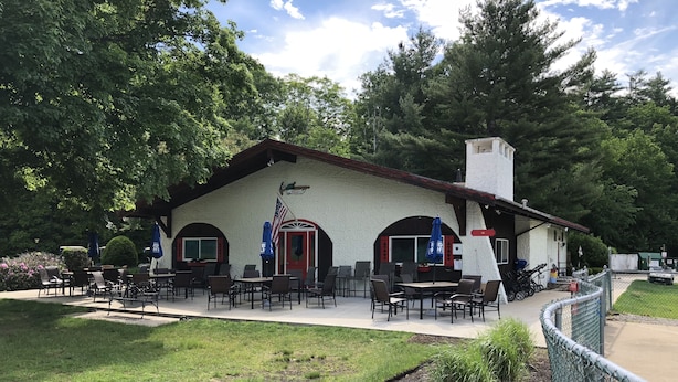 Un edificio rústico con asientos al aire libre y un área cercada.