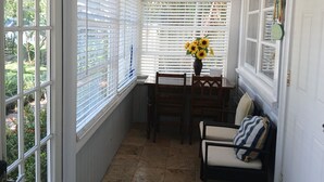 A sunlit room with a dining table, chairs, and a vase with sunflowers. -  BEAUTIFUL PRIVATE COTTAGE   (Lake Worth)