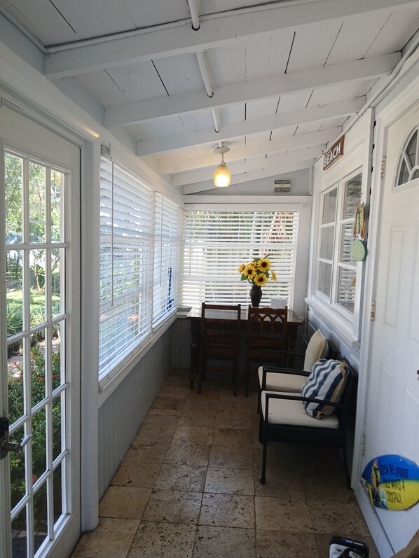 A sunlit room with a dining table, chairs, and a vase with sunflowers.