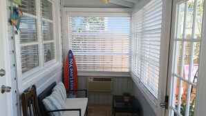 A sunroom with a bench, a small table, and a surfboard decoration. -  BEAUTIFUL PRIVATE COTTAGE   (Lake Worth)