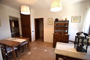 Un coin repas avec une table et des chaises en bois, un meuble encastré en bois doté d’étagères, et deux lampes suspendues.