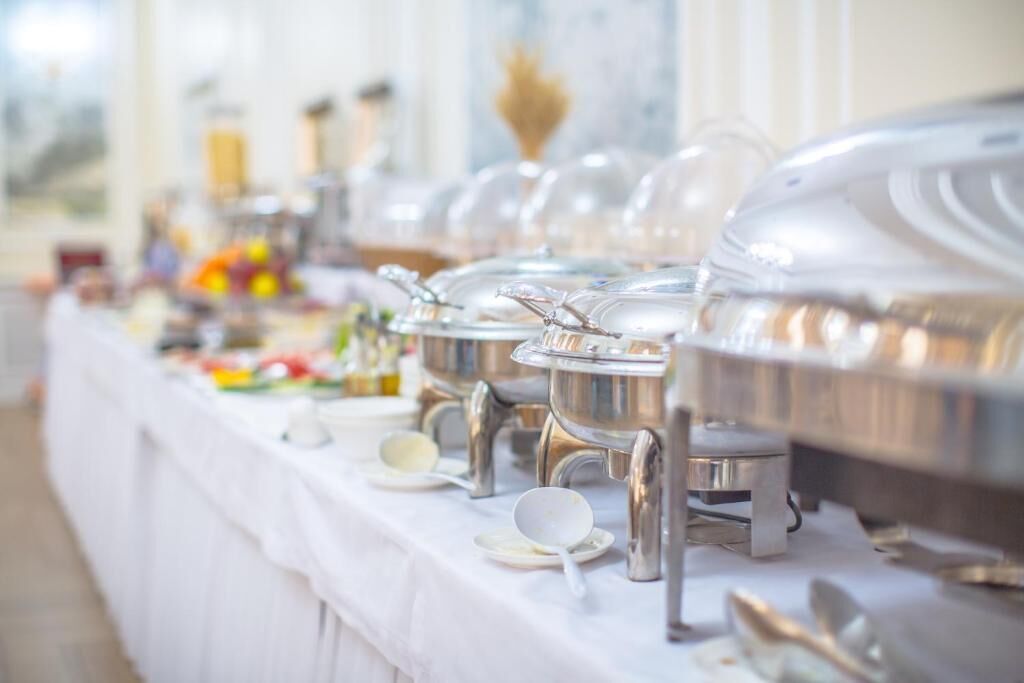 A buffet setup with multiple serving stations, each with a covered dish and a spoon.