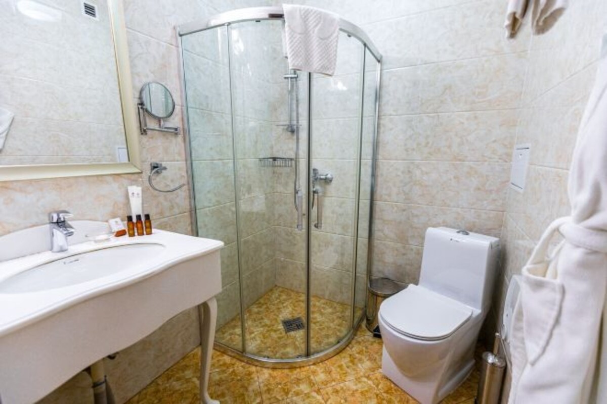 A bathroom with a glass-enclosed shower, a white sink, and a toilet.