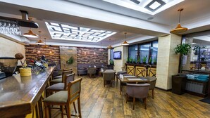 A modern bar area with wooden flooring, bar stools, and pendant lighting. - The Plaza Hotel (Almaty)
