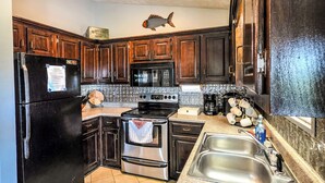 Una cocina con armarios de madera, un refrigerador de acero inoxidable, un horno, un microondas y un lavamanos.