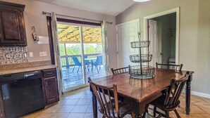 Una cocina con una mesa de comedor, sillas, horno empotrado y puerta corrediza de vidrio que da a un patio exterior.