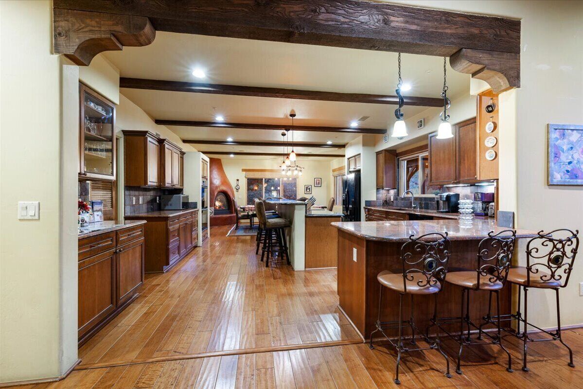 A spacious kitchen with wooden cabinets, a central island with bar stools, and a chandelier.