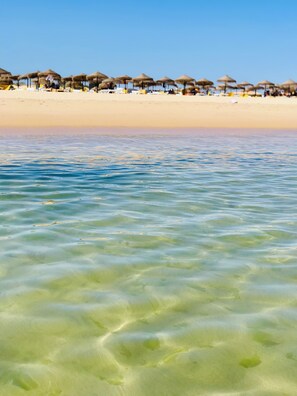 A beach with clear shallow water, umbrellas, and beach chairs. - T2 Terrace, Wifi, Air Conditioning and Swimming Pool - Comfortable and Relaxing Holiday (Cabanas de Tavira)
