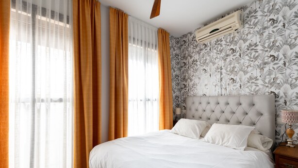 Un dormitorio con una cama grande, cabecera y ventana con cortinas.