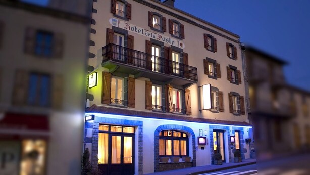 A hotel with a sign reading "Hotel della Poste". It features multiple balconies with wooden railings and stone accents. - Hôtel de la Poste (Pontgibaud)