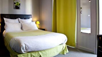 A hotel room with a large bed, two bedside lamps, a green accent wall, and a mirror.