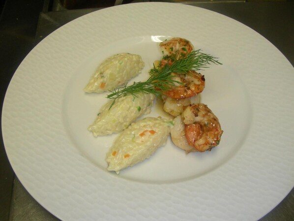 Un plato con dumplings y camarones, adornado con eneldo.