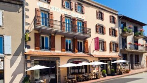 A hotel with outdoor seating, a crosswalk, and a clear blue sky. - Hôtel de la Poste (Pontgibaud)