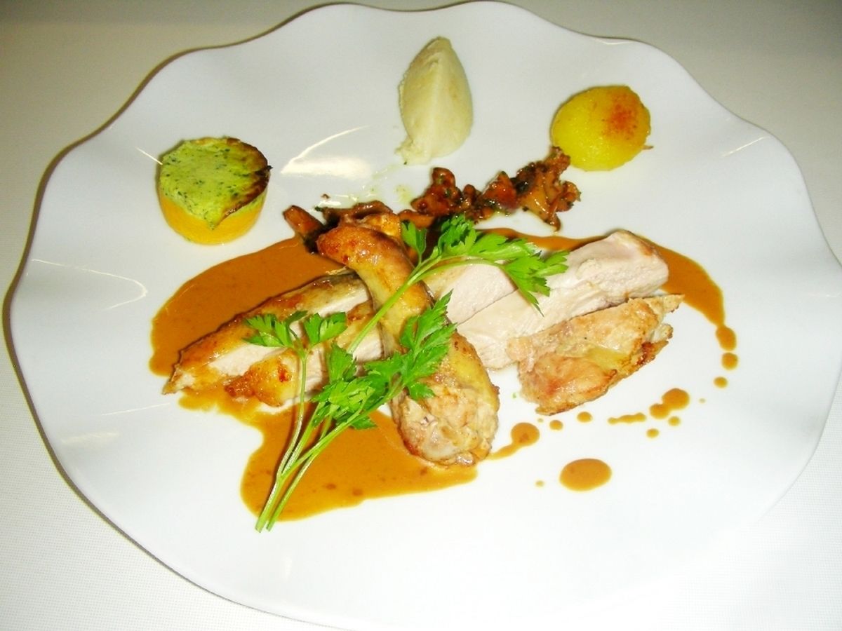 A plate of food with various items including a piece of meat, a lemon, and some greens.