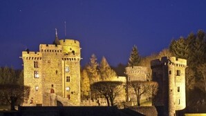 A medieval castle with a central tower, a smaller round tower, and a fortified wall. - Hôtel de la Poste (Pontgibaud)