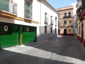A narrow street with a green gate and a white building with a balcony.