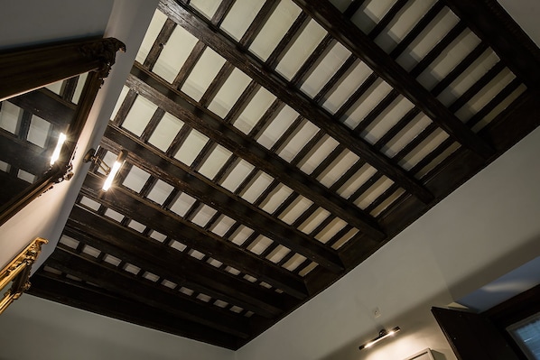 A room with a sloped ceiling featuring exposed wooden beams and a skylight.