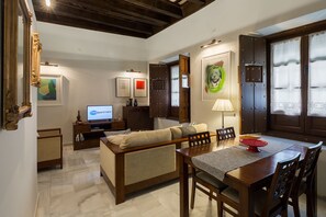 A living room with a sofa, a dining table, and a TV displaying 'veo apartment'.