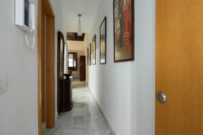 A hallway with a wooden door, a telephone, and framed artwork on the walls. - 1 bedroom in Triana, free parking (Sevilla)