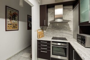 Een moderne keuken met roestvrijstalen apparatuur, een marmeren aanrechtblad en een inbouwoven.