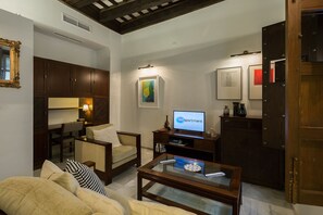 Una sala de estar con un sofá, sillones, una mesa de centro, un televisor y una estantería.