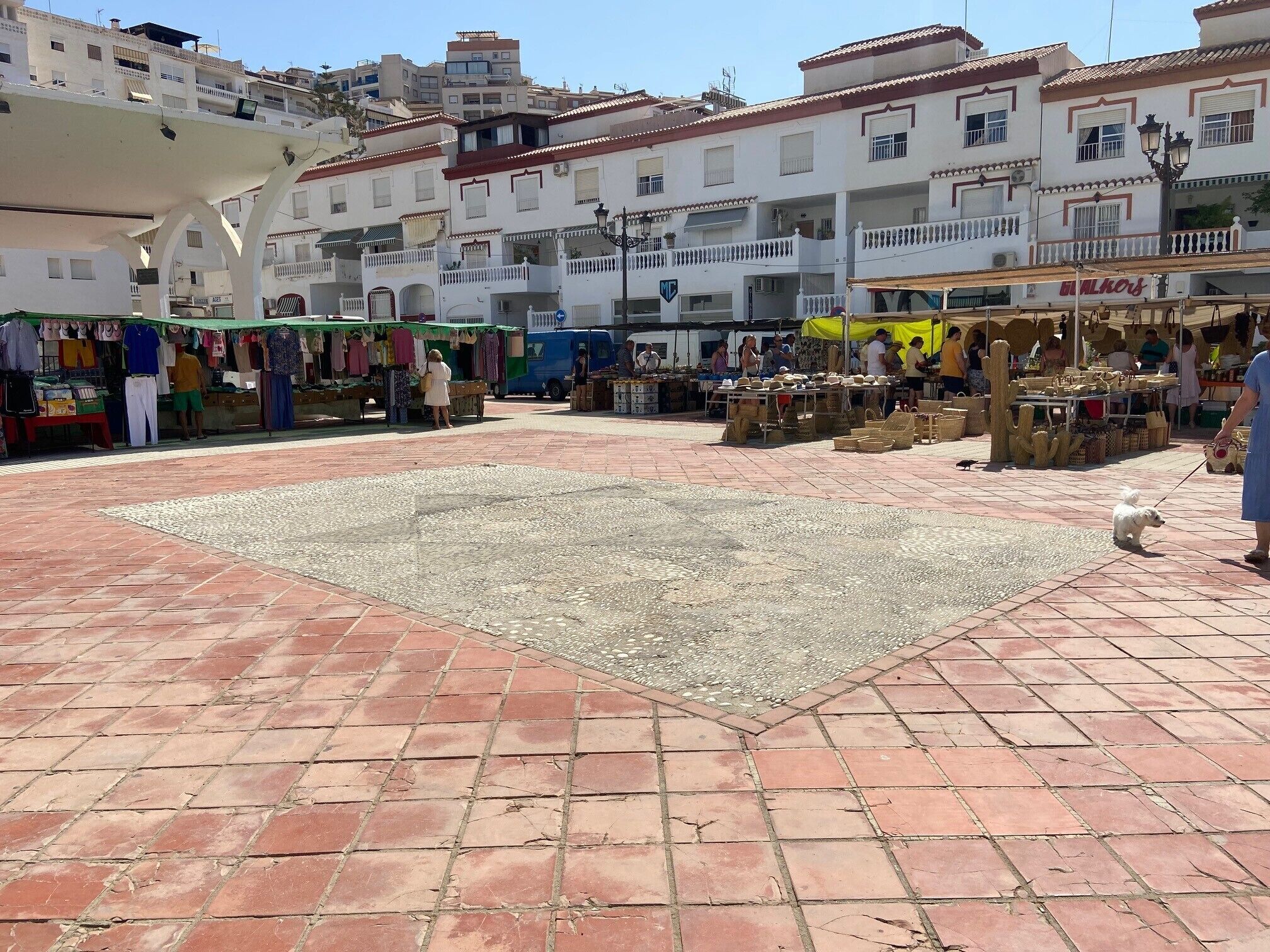Une zone commerciale avec des étals et une place dallée.