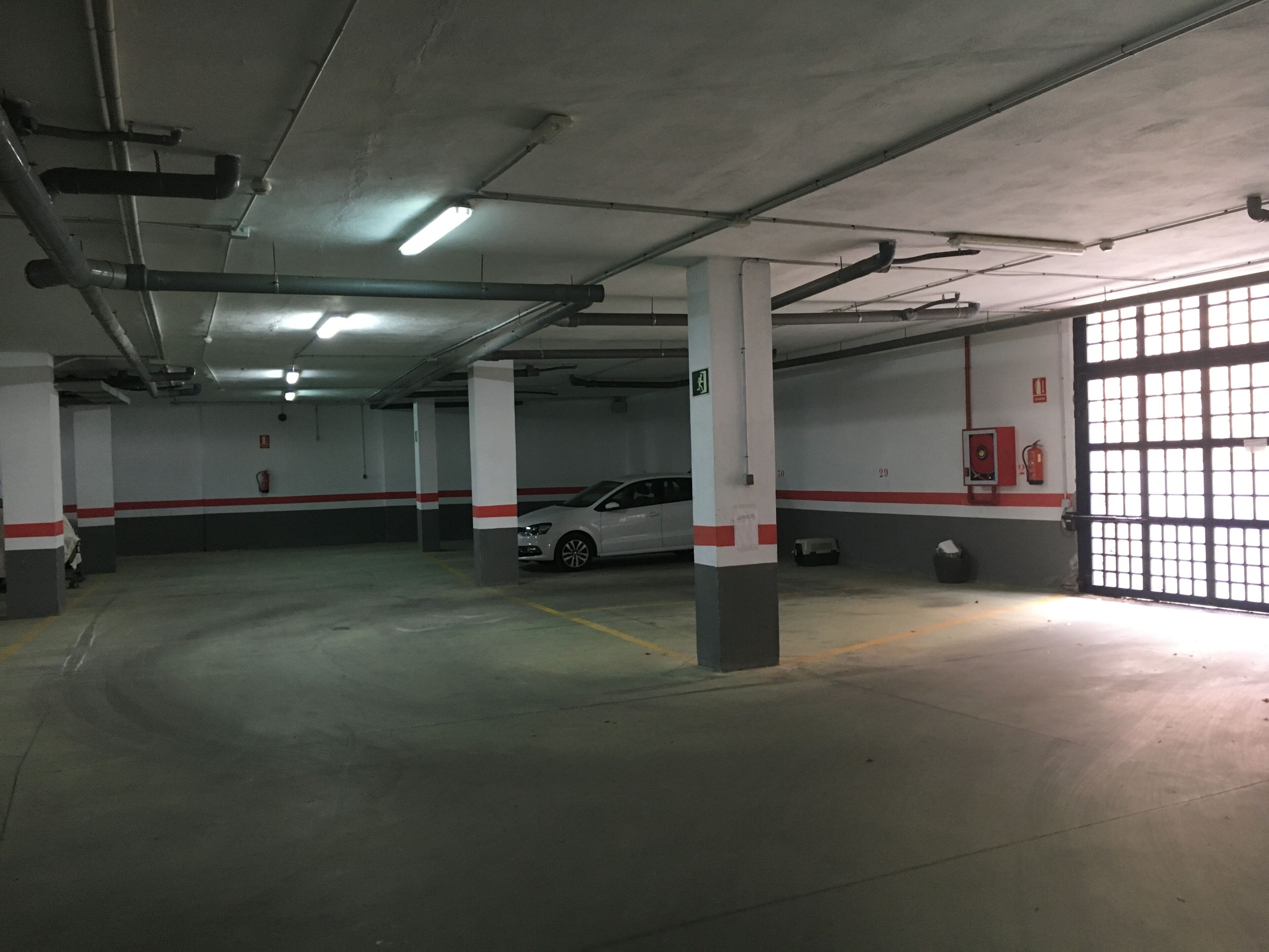 A multi-level parking garage with concrete pillars, emergency equipment, and a fire extinguisher.
