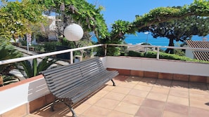 Un balcon avec un banc, une lanterne en papier blanche et une vue sur la mer.