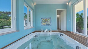 Ett spa-rum med bubbelbadkar, trägolv och utsikt över omgivningarna.