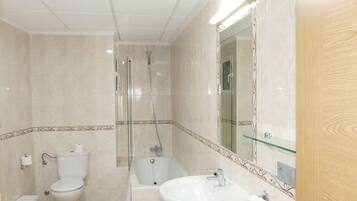 Un baño con inodoro, bidé, bañera y lavamanos.