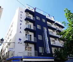A multi-story hotel named "OLYMPIA" with balconies and air conditioning units.