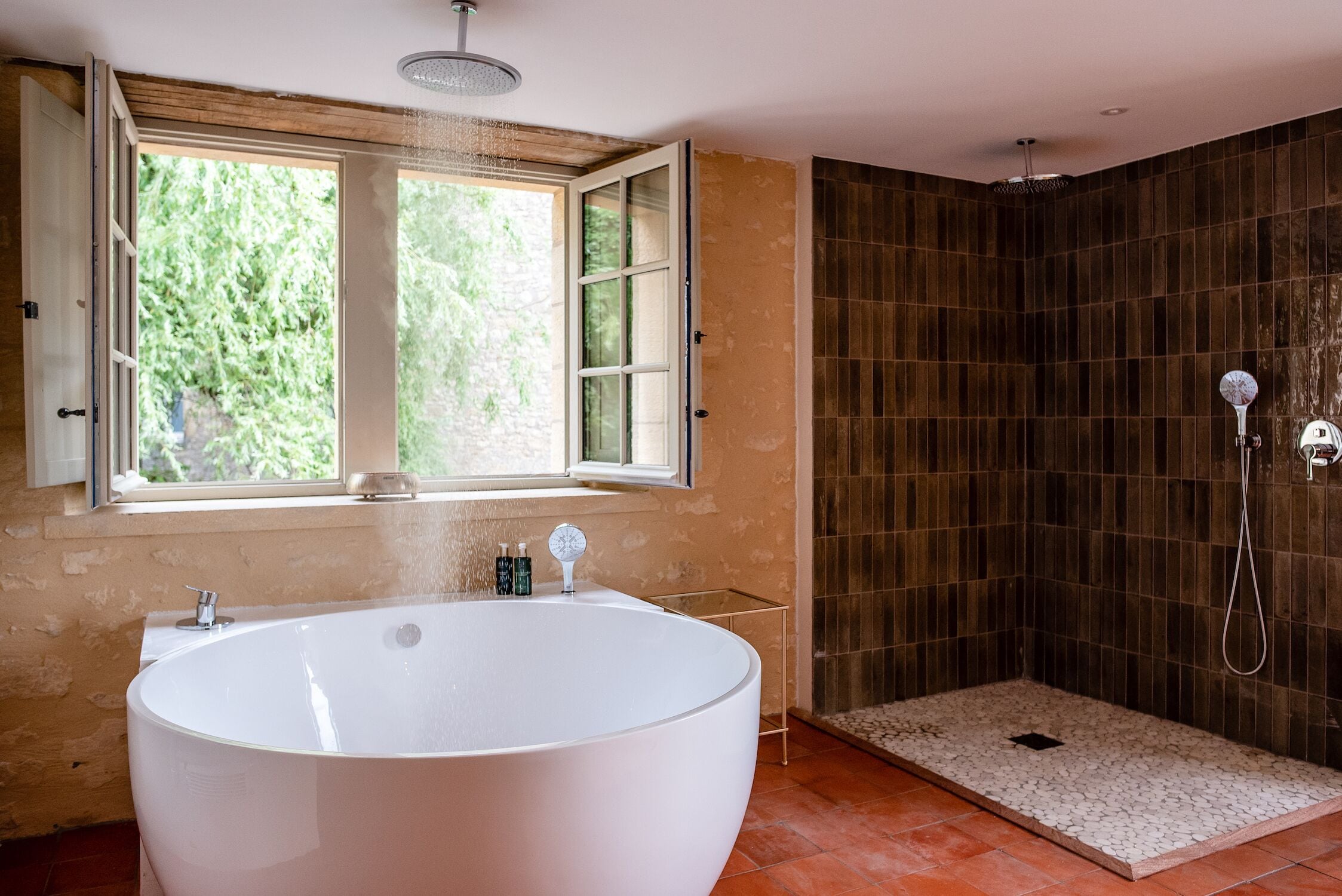 Un baño moderno con una bañera independiente, zona de ducha y ventana que proporciona luz natural.