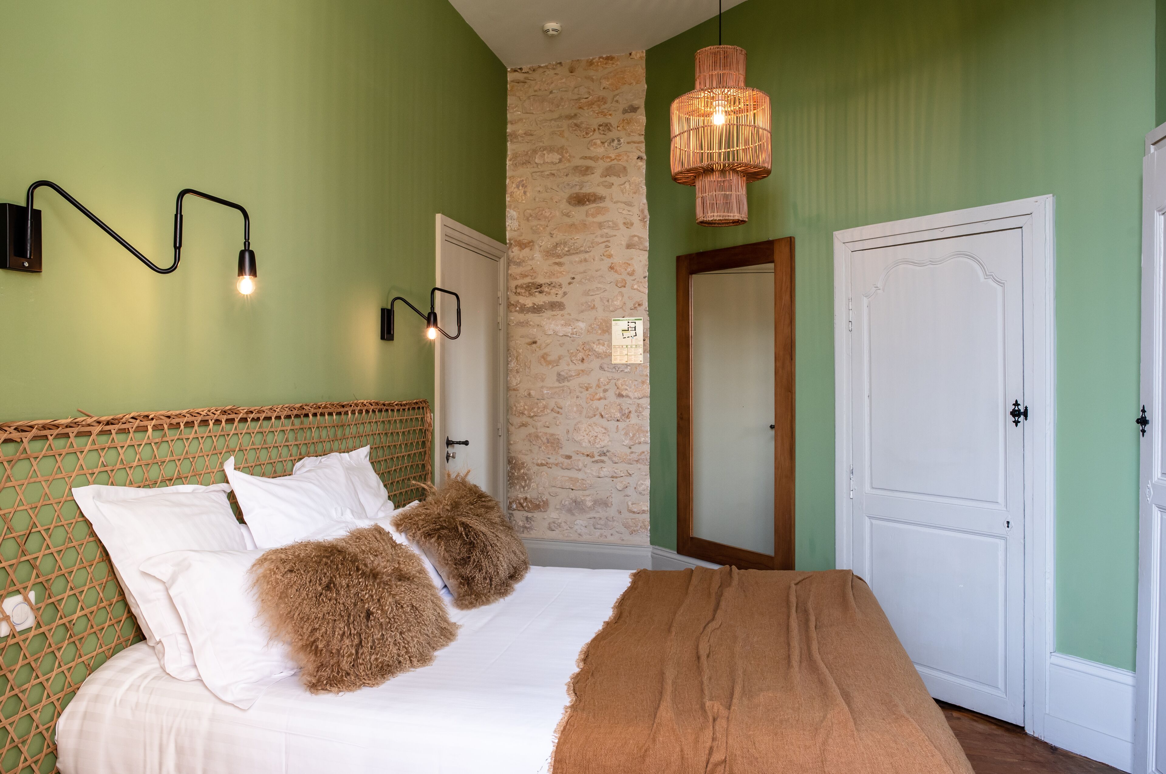 Ein Schlafzimmer mit einem Bett, zwei Nachttischlampen, einer Steinwand und zwei Türen.