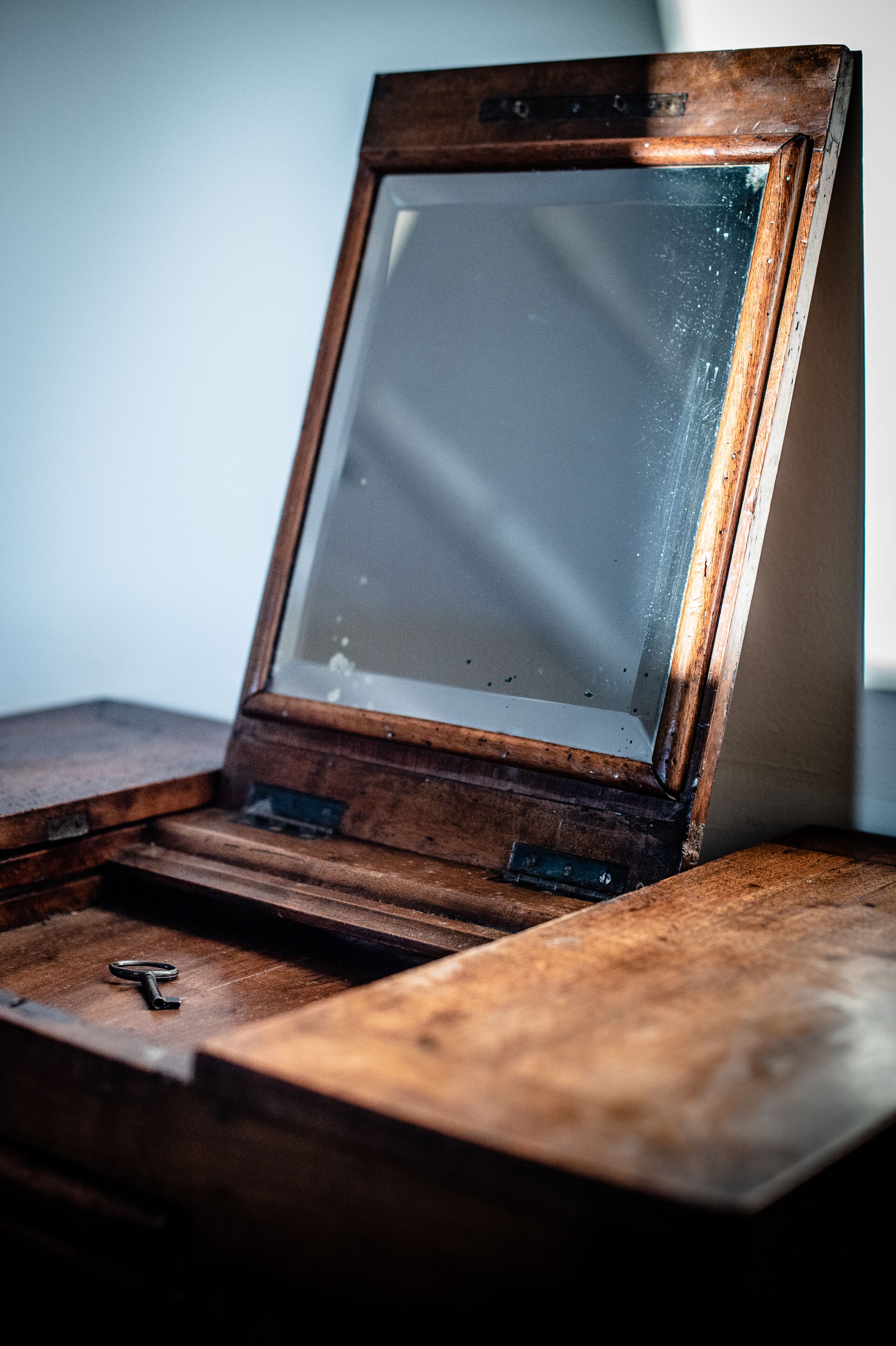 Un mueble de madera con puerta de cristal, una llave encima y un cierre metálico.